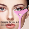 Pink curved makeup guide held below the eye during mascara application