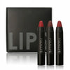 Three lip crayons standing in front of a closed black box