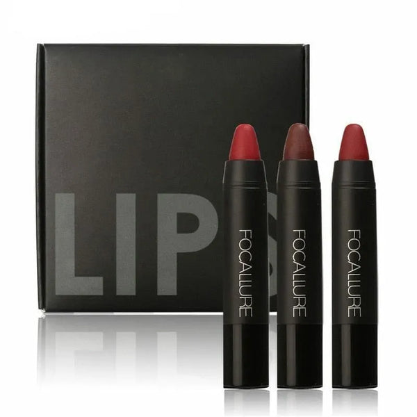 Three lip crayons standing in front of a closed black box