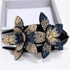 Dark blue and pale gold rhinestone flowers on a black hair claw
