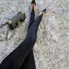 Underfoot straps on black stirrup leggings styled with pointed-toe pumps