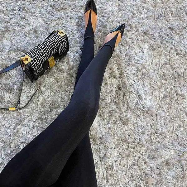 Underfoot straps on black stirrup leggings styled with pointed-toe pumps