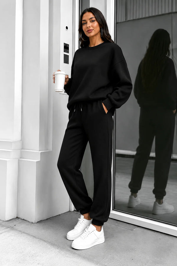 Black crewneck sweatshirt and matching joggers worn with white sneakers